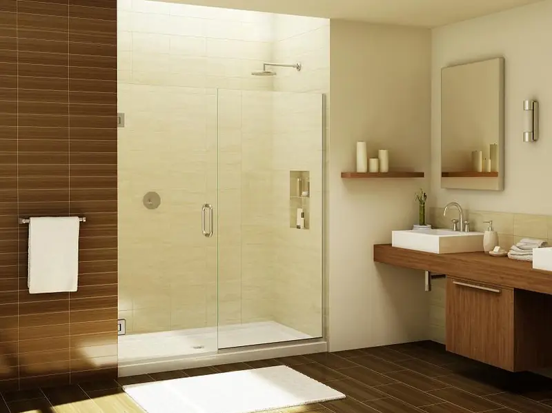 Frameless glass shower door in a warm, modern bathroom with wood vanity