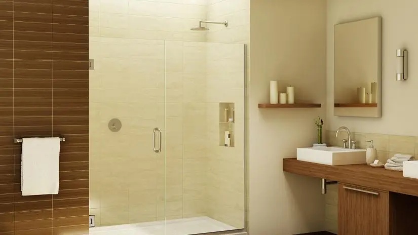 Frameless glass shower door in a warm, modern bathroom with wood vanity