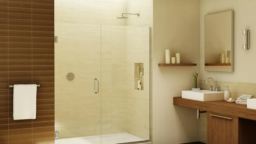 Frameless glass shower door in a warm, modern bathroom with wood vanity